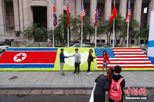 當地時間2月26日，越南首都河內，民眾在“金特會”造型花壇前握手合影。朝美領導人第二次會晤將于2月27日－28日在越南首都河內舉行。<a target='_blank' >中新社</a>記者 富田 攝
